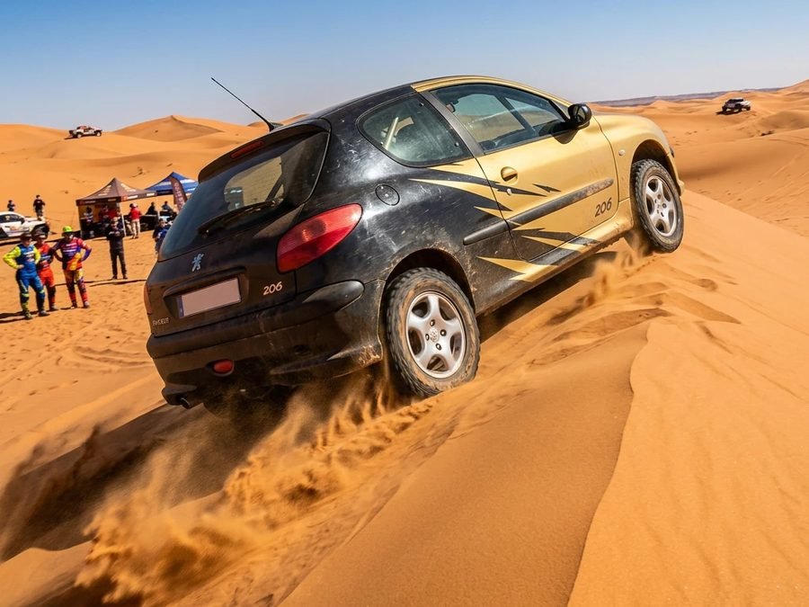 Une Peugeot 206 à l'assaut d'une dune lors d'un raid dans le désert marocain